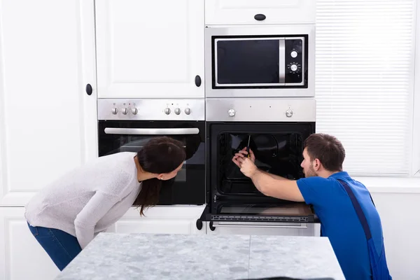 Sonriente Joven Mujer Mirando Técnico Fijación Horno Cocina —  Fotos de Stock