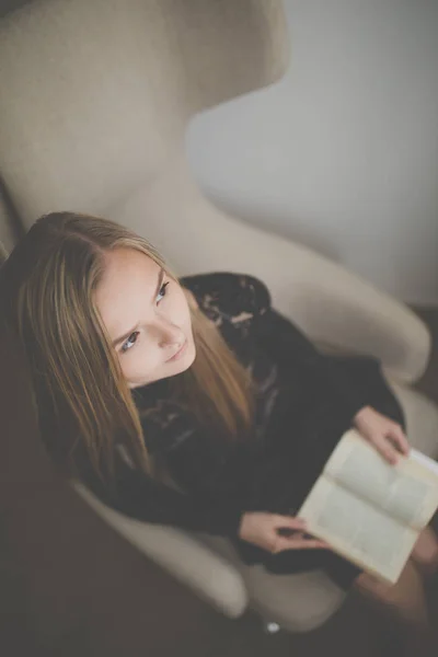 Mulher Jovem Bonito Lendo Livro Uma Cadeira Designer Cor Tonificada — Fotografia de Stock