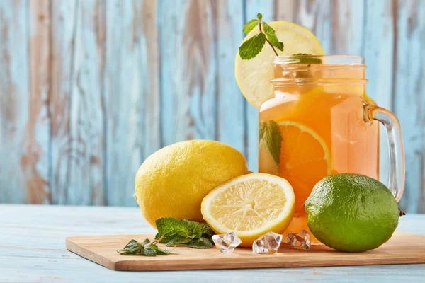 氷と柑橘類のレモネード ミントの葉 青の木製のテーブルの上に立ってレモンとライムスライス 柑橘類と自家製レモネード 健康的な冷たい飲み物 — ストック写真