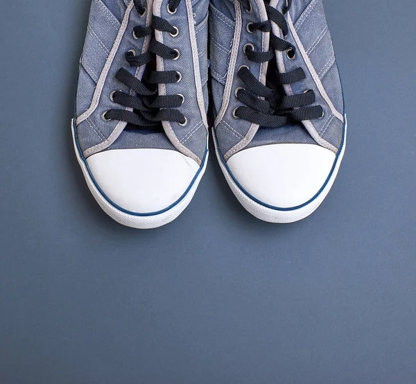 一双破旧的旧纺织蓝色运动鞋 黑色背景上的白色鞋带 顶视图 — 图库照片