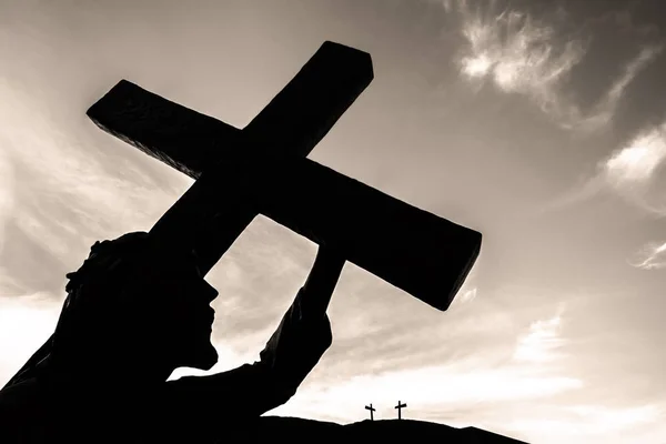十字架を背負ったイエスのブロンズ像 イースターのコンセプト 復活などに最適です 雲を背景に空 — ストック写真