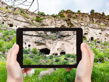 travel concept - tourist photographs of rock-cut caves in Ihlara Valley of Aksaray Province in Cappadocia on smartphone in Turkey in spring clipart