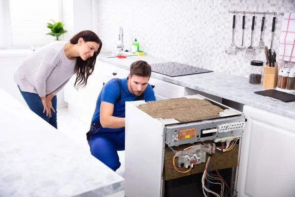 微笑的女人背后的技术人员修复洗碗机在厨房 — 图库照片