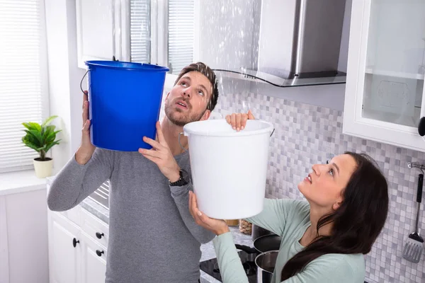 Close Worried Young Couple Collecting Water Leaking Ceiling Blue Bucket — Stock Photo, Image