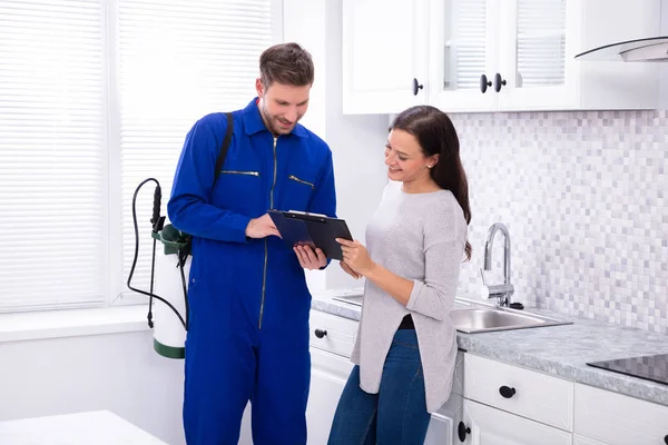 Young Male Pest Control Worker Showing Invoice Woman Domestic Kitchen — Stock Photo, Image