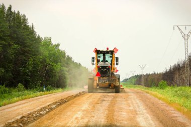 Traveling on a gravel road behind a grader. clipart