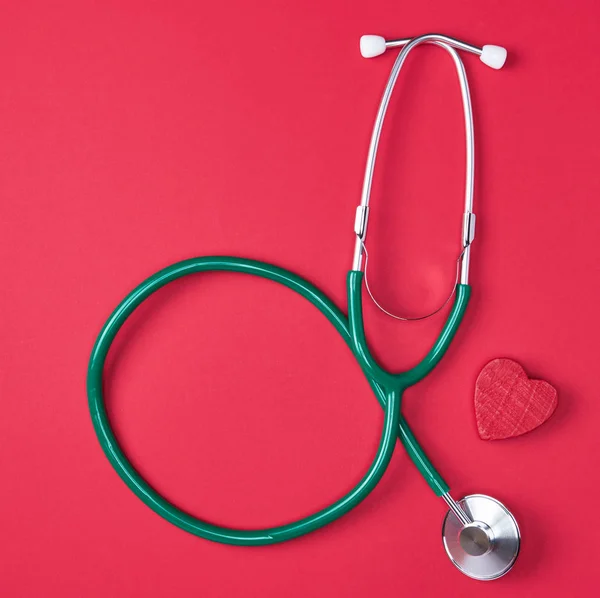 Estetoscópio Médico Verde Coração Madeira Fundo Vermelho — Fotografia de Stock