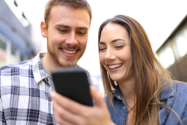 通りでオンライン コンテンツをスマート フォンをチェックする幸せなカップルの正面肖像画 — ストック写真
