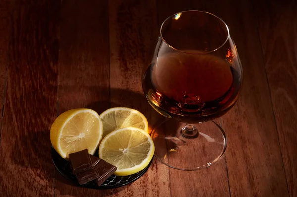 Stilleven Met Glas Met Cognac Bord Met Stukjes Citroen Chocolade — Stockfoto