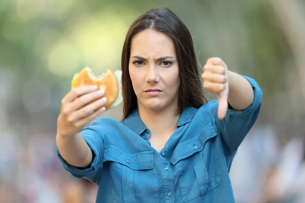 Vista Frontal Una Mujer Molesta Sosteniendo Una Hamburguesa Con Pulgar —  Fotos de Stock