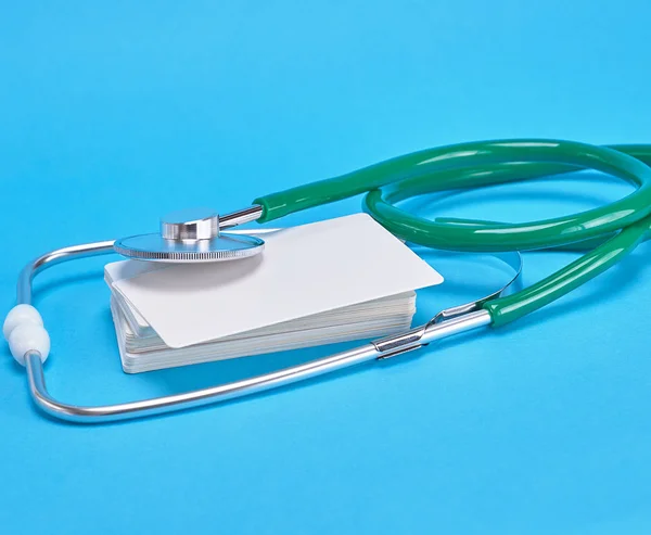医療聴診器の緑と青の背景に空の紙名刺 — ストック写真