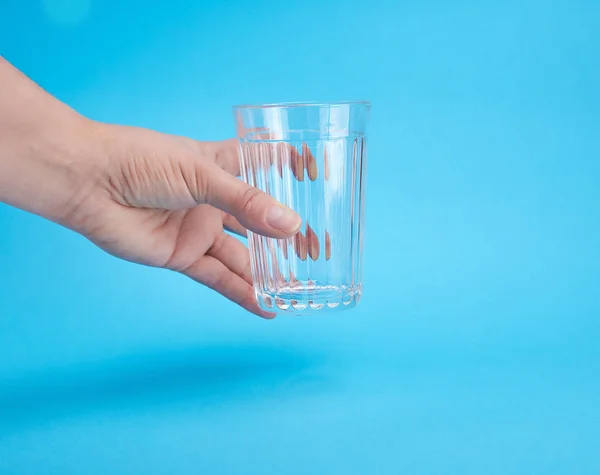 Mão Mulher Segurando Copo Transparente Vazio Fundo Azul — Fotografia de Stock
