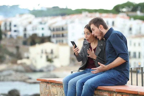 Überraschtes Paar Urlaub Liest Nachrichten Auf Einem Smartphone Und Sitzt — Stockfoto
