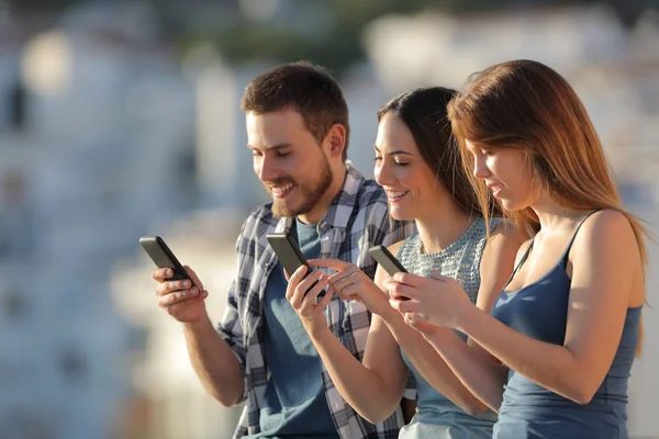 町の郊外でスマートフォンを使っている3人の友人のグループ — ストック写真