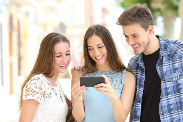 路上に立っているスマートフォンでメディアを見ている10代の友人3人 — ストック写真