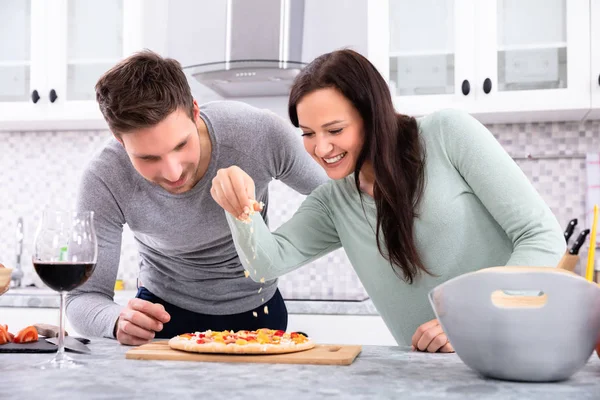 Sorrindo Casal Polvilhando Queijo Pizza Cozinha — Fotografia de Stock