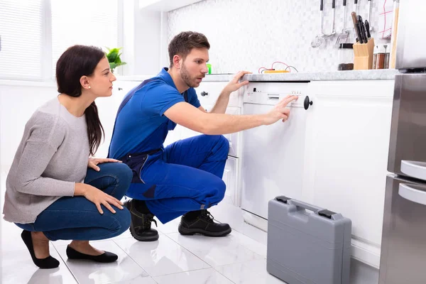 Serviceman Agachado Chão Cozinha Pressionando Botão Máquina Lavar Louça Enquanto — Fotografia de Stock