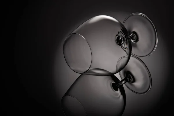 Silhouette of empty snifter glass (brandy snifter, brandy bowl, cognac glass, or balloon) on a black background with reflection. Glassware for aged brown spirits. Contour with gradient and highlights