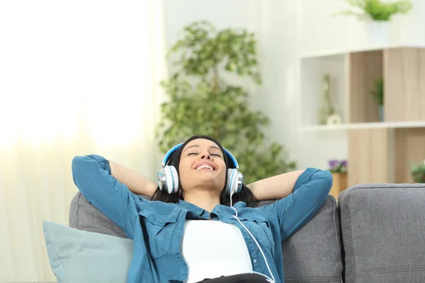 坐在客厅的沙发上听音乐的快乐女人 — 图库照片