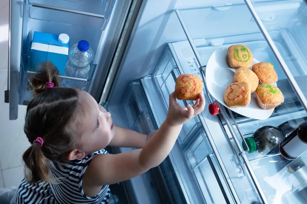 Innocente Sorridente Ragazza Cercando Prendere Cupcake Dal Frigorifero Cucina — Foto Stock