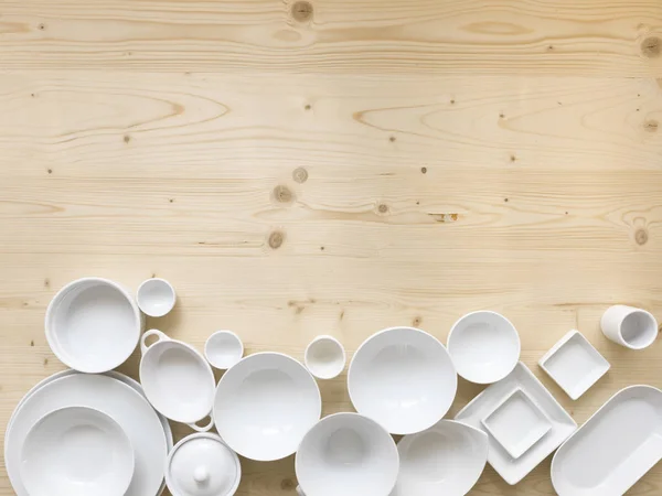 modern, white crockery, in different designs, stands on a light wooden background, photo taken from above