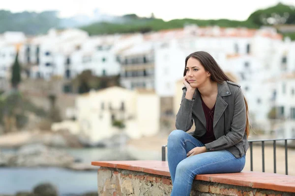 一个忧心忡忡的女人坐在海滨小镇的窗台上 望着远方 — 图库照片