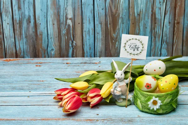 色彩艳丽的复活节彩蛋 复活节兔子和春天的花朵在木制的背景上 有复制的空间 复活节背景的贺卡 — 图库照片