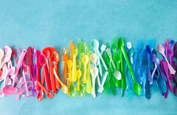 Variety of colorful plastic cutlery on blue background