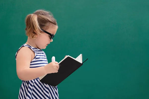 Cute Little Girl Standing Front Chalkboard Reading Book — Stock Photo, Image