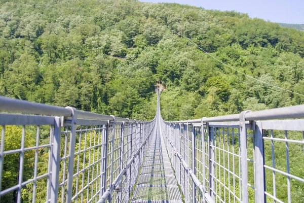 树木繁茂的曼塔格纳的两侧与悬挂在蓝天下山谷上方的铁桥连接在一起 — 图库照片