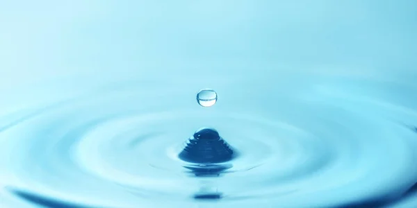 青い水の中に水滴が落下し 波紋を形成し クローズアップ — ストック写真