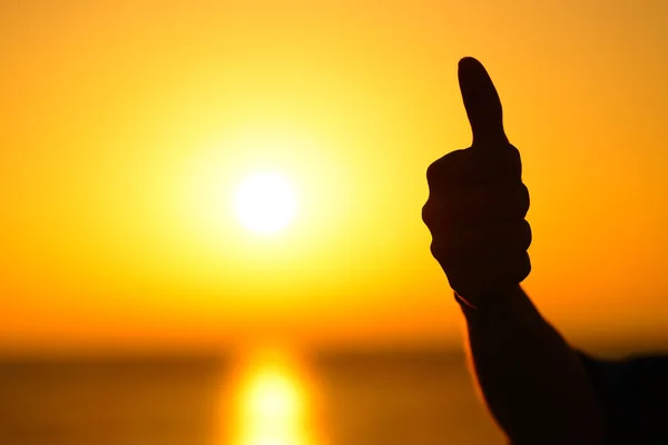 关闭一个女人的手剪影手势拇指在日落与温暖的太阳在背景 — 图库照片