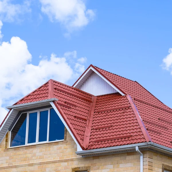 The house with plastic windows and a roof of corrugated sheet. Roofing of metal profile wavy shape on the house with plastic windows.