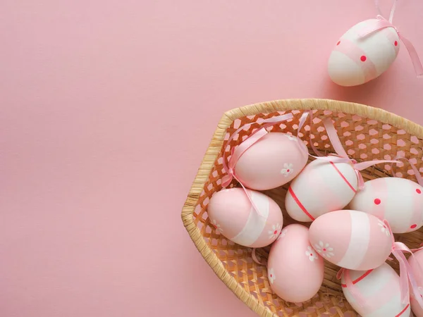 Pink Easter decoration with a basket on a pink background, space for your text on the left side