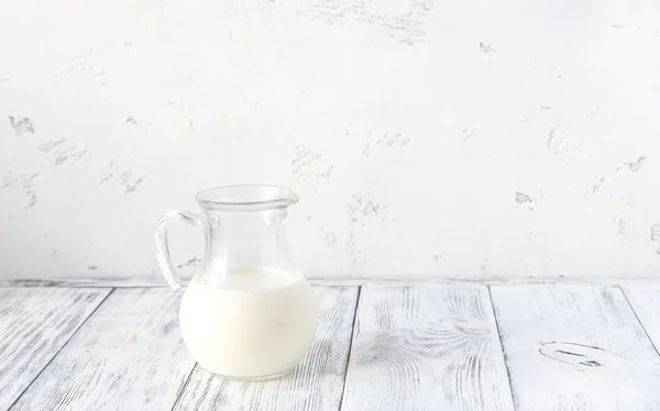 Jug of milk on the wooden background