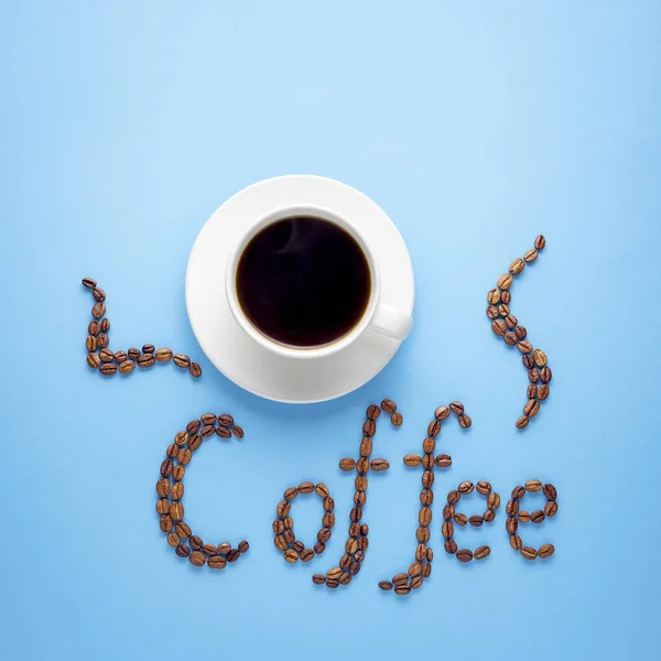 创意食品概念照片一杯咖啡饮料与蓝色背景上的豆子制成的标志 — 图库照片