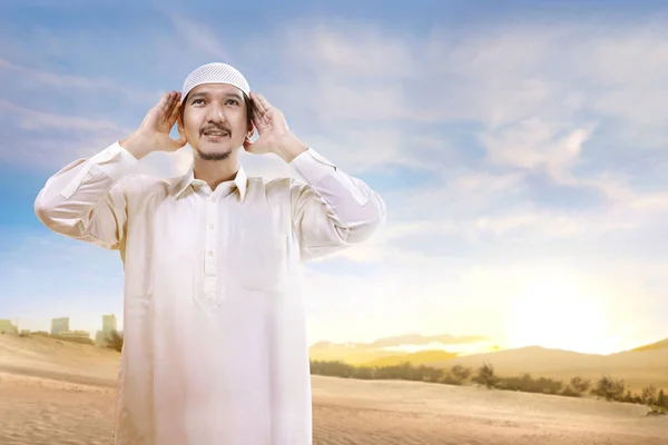 Sorrindo Asiático Muçulmano Homem Com Boné Orando Areia Com Fundo — Fotografia de Stock