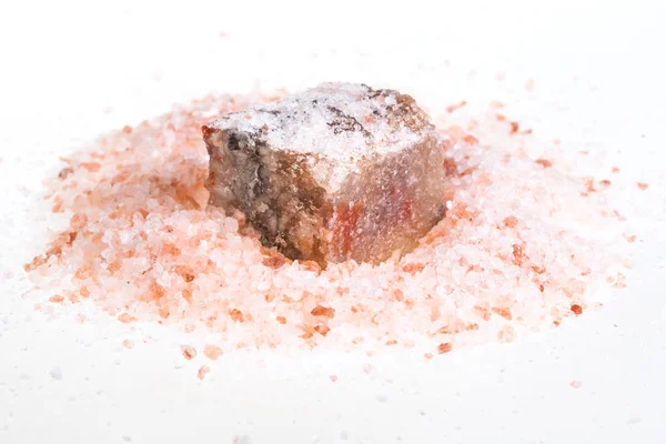 白い背景の上の粒ピンク ヒマラヤ塩の杭で天然の岩塩ミネラル — ストック写真