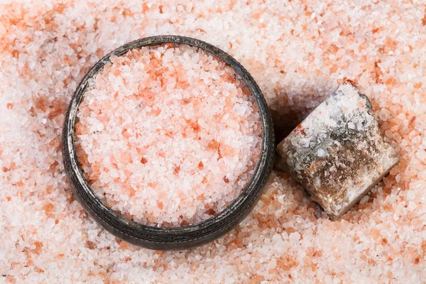 top view of old silver salt cellar, rough natural pink Halite mineral and grained Himalayan Salt close up