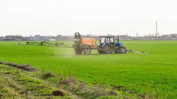 高轮子的拖拉机正在用小麦做肥料 使用精细分散的喷雾化学品 用喷雾装置进行精细分散肥料的拖拉机 — 图库照片