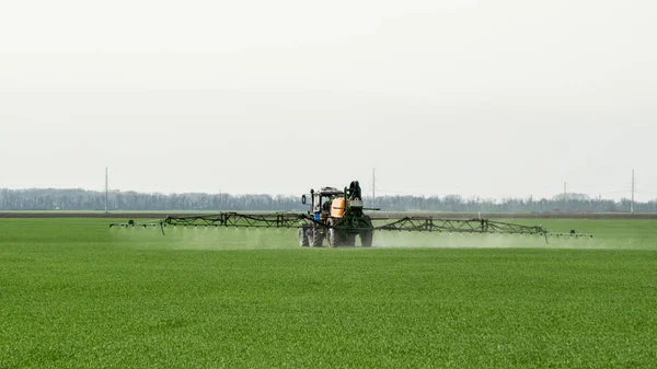 高轮子的拖拉机正在用小麦做肥料 使用精细分散的喷雾化学品 用喷雾装置进行精细分散肥料的拖拉机 — 图库照片