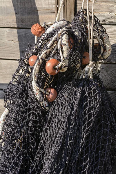 Detail of black fishing net with floats hanging on the old wooden boat.