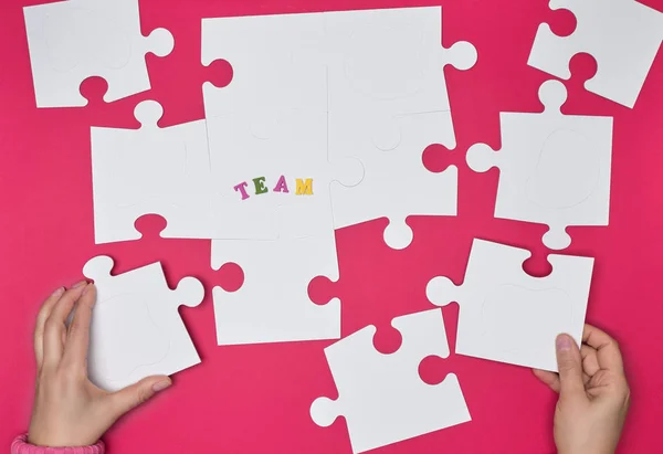 Mão Feminina Coloca Grandes Puzzles Brancos Fundo Vermelho Equipe Inscrição — Fotografia de Stock