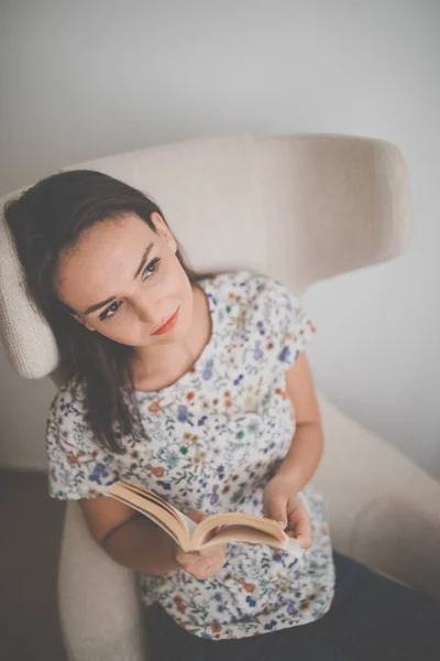 Mulher Jovem Bonito Lendo Livro Uma Cadeira Designer Cor Tonificada — Fotografia de Stock