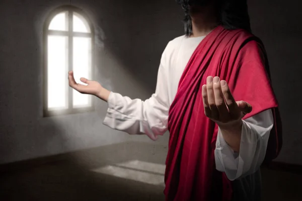 耶稣的基督用张开的手掌举手祷告 用窗户外面的光在屋里向神祷告 — 图库照片