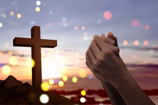 基督徒十字架和男性手与祈祷的位置在日落背景 — 图库照片