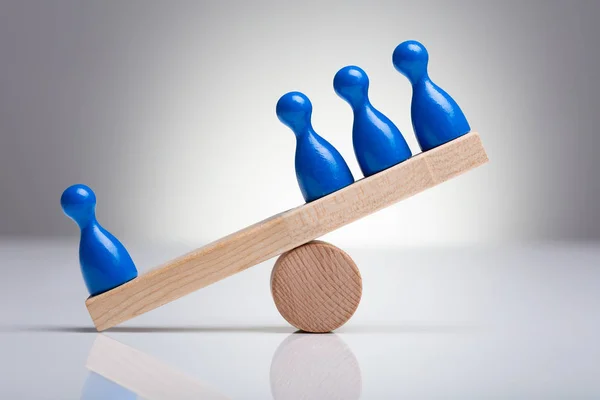 Blue Pawns Figures Balancing Wooden Seesaw Desk — стоковое фото