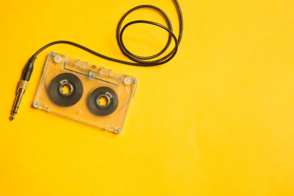 黄色の背景にレトロなカセットテープとオーディオジャック コピースペース — ストック写真