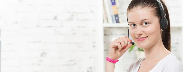 Pretty young smiling woman with a headset and computer