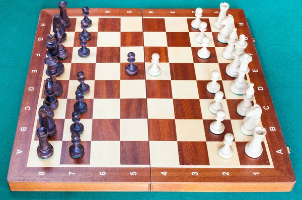 木棋盘的侧视图与第一棋棋子移动在绿色贝泽表 — 图库照片